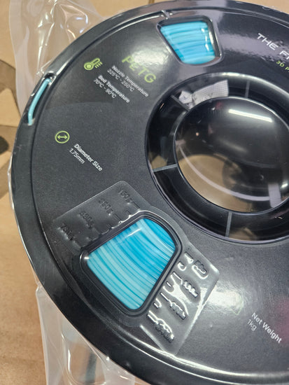 Spool of black PETG filament with blue labels on a clear background