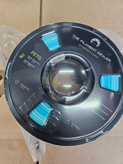 Spool of filament labeled 'The Filament Dealer' on a cardboard background