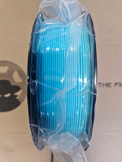 Blue spool of filament on a beige background