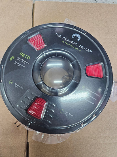 Spool of filament labeled 'The Flexment Dealer' on a cardboard background