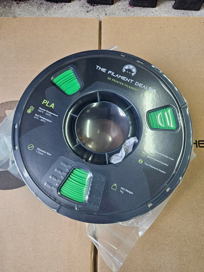 Spool of filament labeled 'PLA' on a cardboard surface