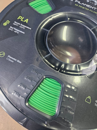 3D printing filament spool with green PLA material on a black background
