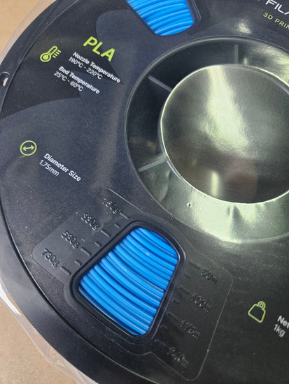 Close-up of a 3D printer nozzle with PLA filament label
