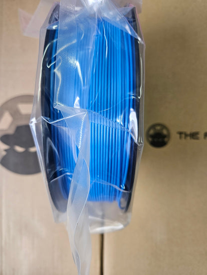 Spool of blue cable in clear plastic packaging on a beige surface