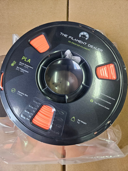 Spool of filament labeled 'The Element Dealer' on a cardboard background