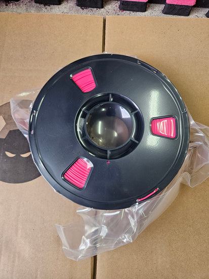 Black and pink object on a cardboard surface with plastic wrap