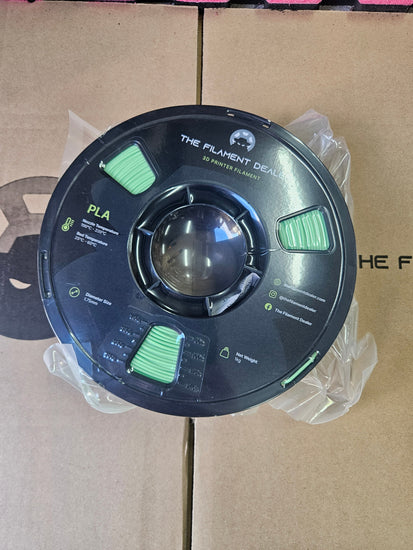 Spool of filament labeled 'PLA' on a cardboard background