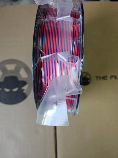 Spool of red and black wire on a cardboard surface