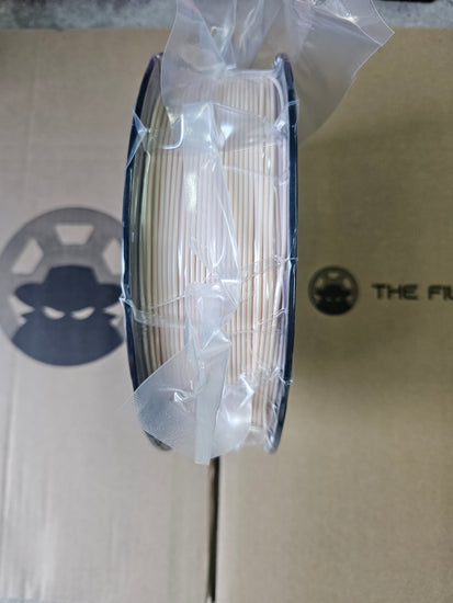 Spool of white thread in a clear plastic cover on a cardboard background