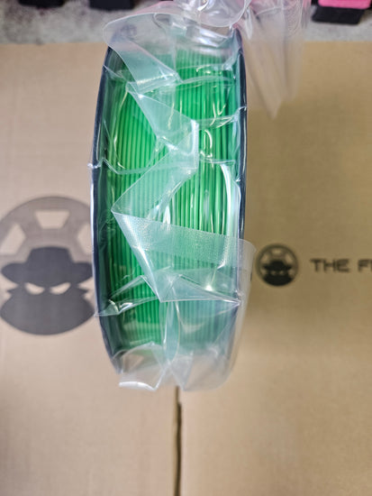 Roll of green electrical wire on a cardboard surface